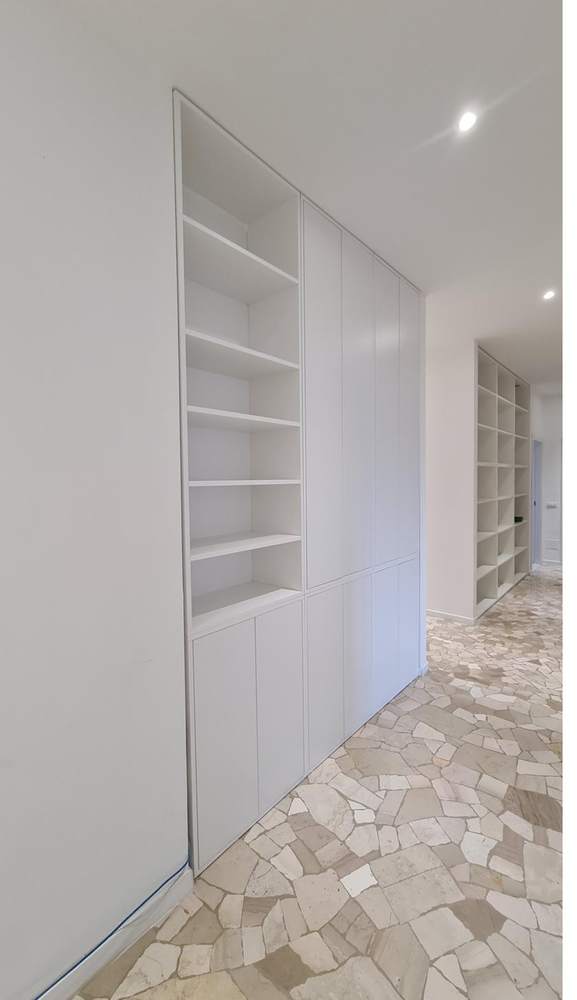 Libreria bianca con il lato superiore inclinato che segue il soffitto